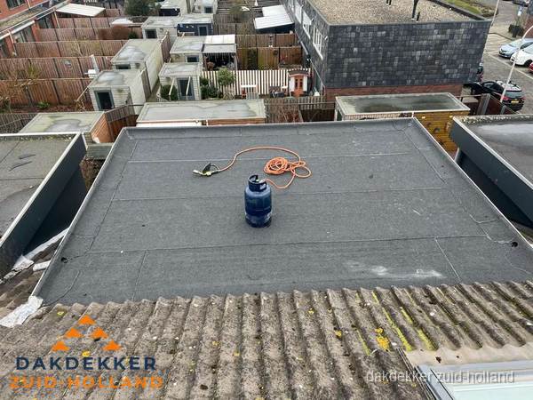 Plat dak met nieuwe bitumen dakbedekking en brandgereedschap in Zuid-Holland