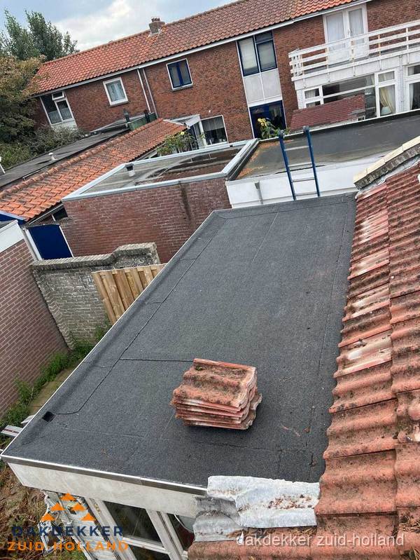 Plat dak aanbouw met bitumen naast schuin pannendak in Zuid-Holland