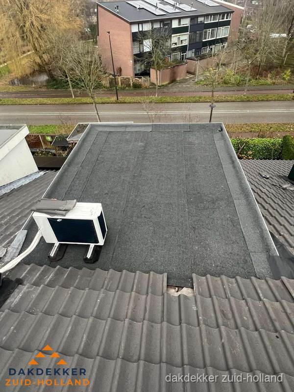 Plat dak inspectie met bitumen bedekking naast schuin pannendak in Zuid-Holland
