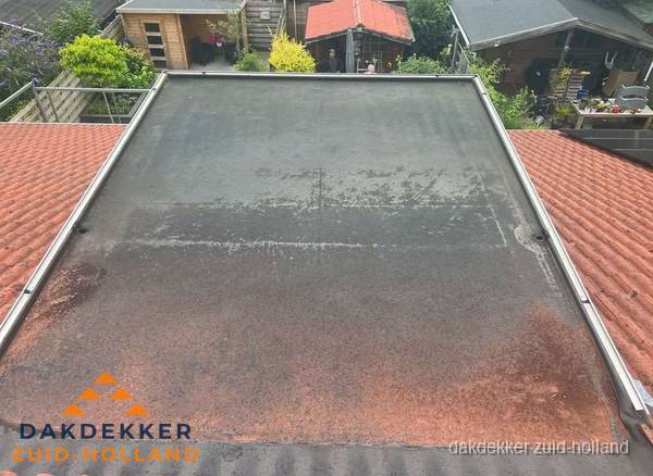 Verouderd plat dak met slijtage tussen schuine daken in Zuid-Holland Verouderd plat dak met slijtage tussen schuine daken in Zuid-Holland