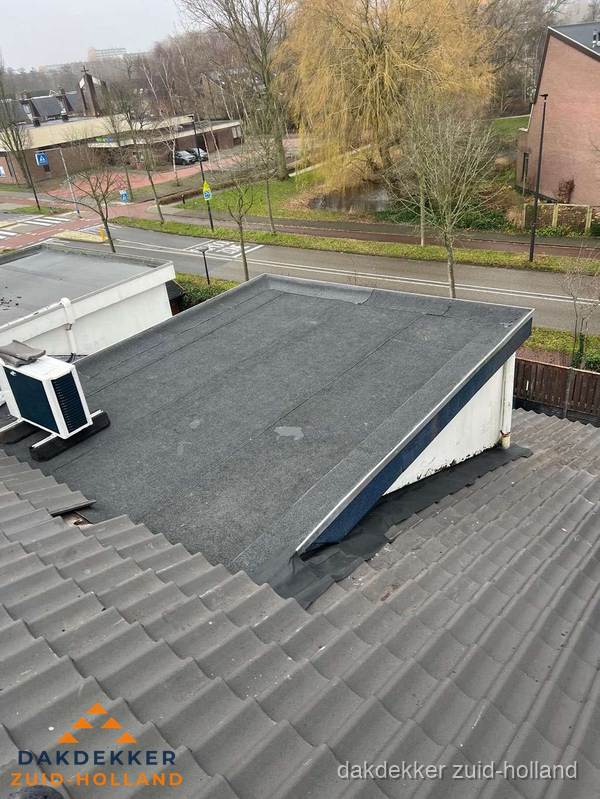 Plat dak met bitumen dakbedekking naast schuin pannendak in Zuid-Holland