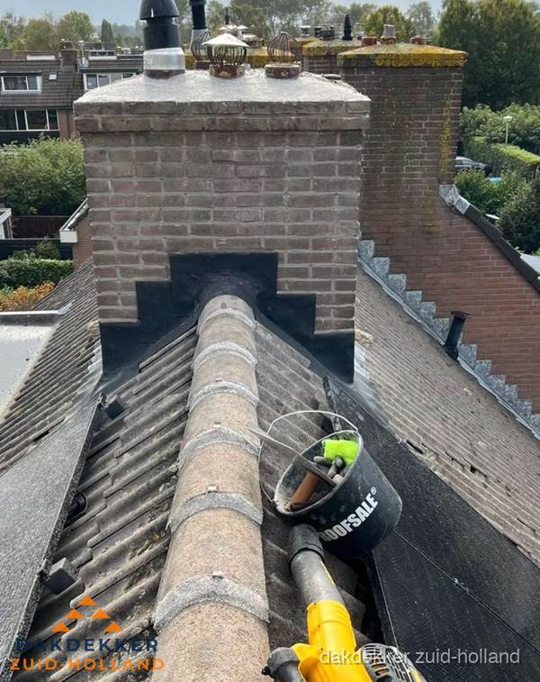 Schoorsteen met loodaansluiting en nokvorst op pannendak in Zuid-Holland
