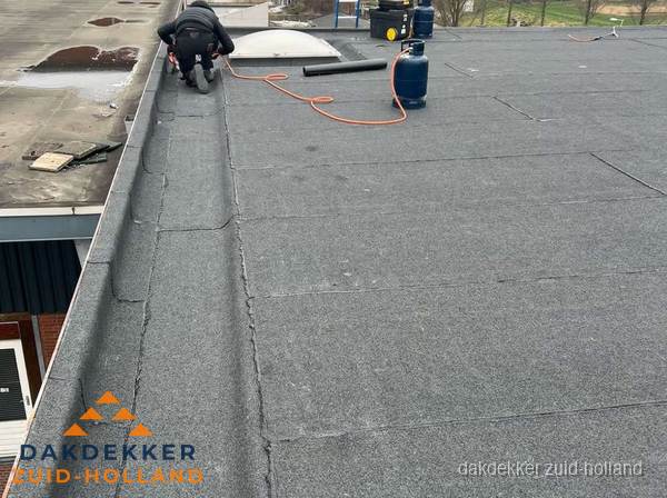 Dakdekker repareert bitumen dakbedekking op groot plat dak in Zuid-Holland