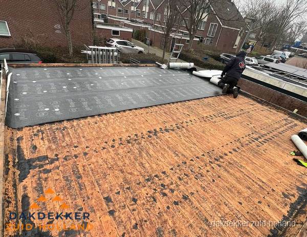 Dakdekker legt onderlaag op plat dak met houten constructie in Zuid-Holland