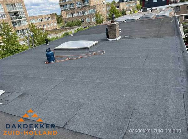 Bitumen dakbedekking op plat dak met lichtkoepel en schoorsteen in Zuid-Holland