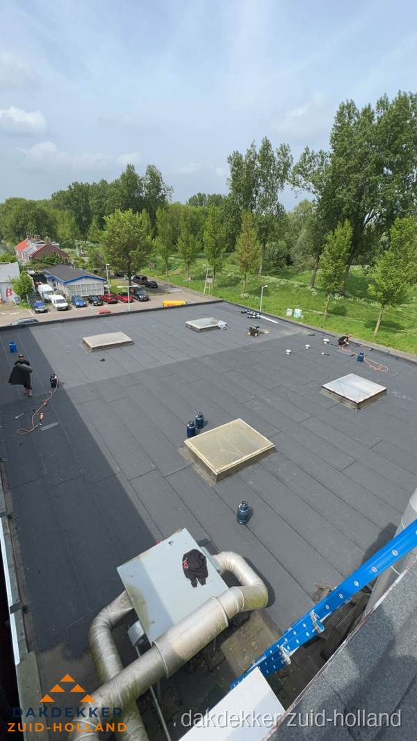 Dakdekker aan het werk op groot plat dak met bitumen in Zuid-Holland