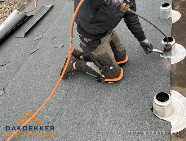 Dakdekker repareert bitumen dakleer bij dakdoorvoer in Zuid-Holland
