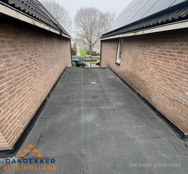 Plat dak met bitumen dakbedekking tussen bakstenen muren in Zuid-Holland