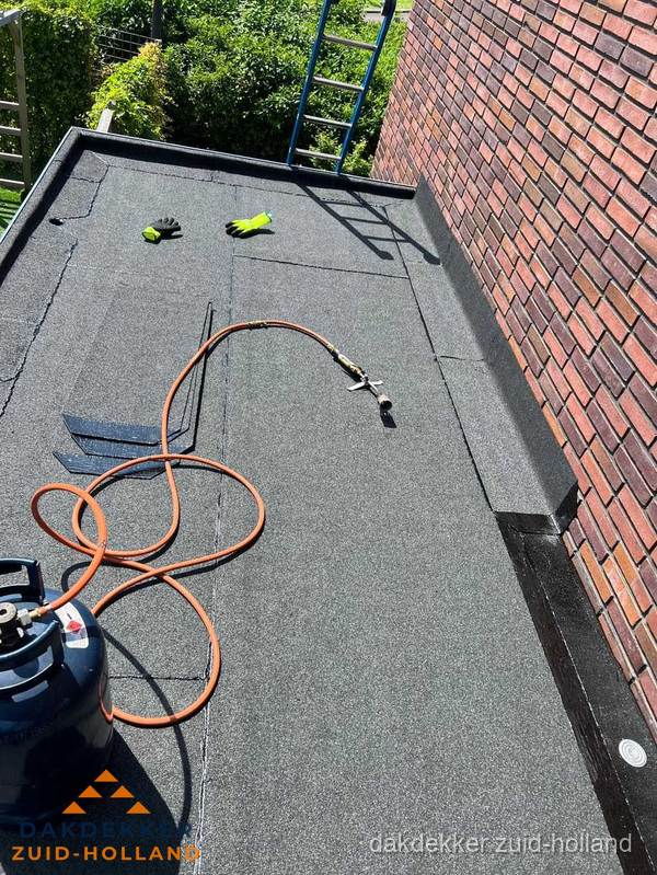 Plat dak met bitumen en brandgereedschap van dakdekkersbedrijf in Zuid-Holland